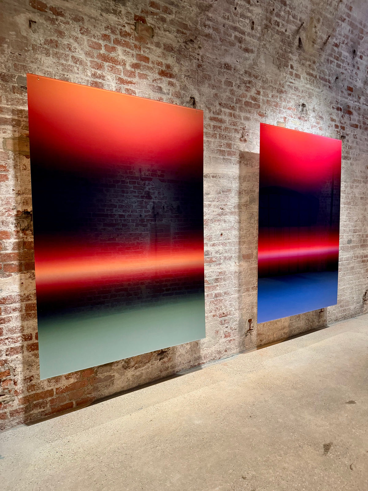 Two HORIZON acrylic glass artworks by Luis West hung side by side as a pair on a brick wall