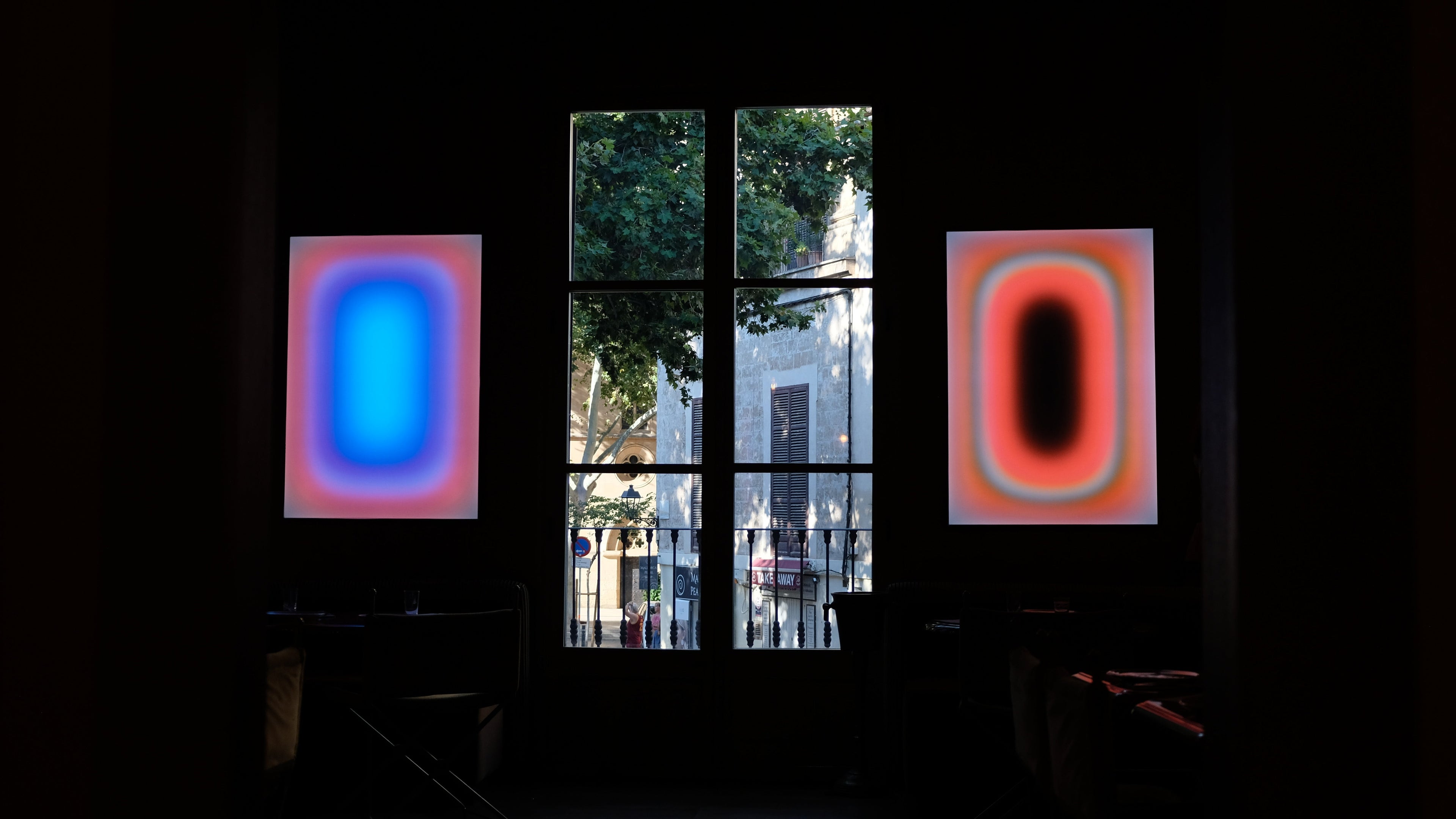 Two illuminated Luis West lightboxes flanking a window, light art in a contemporary interior