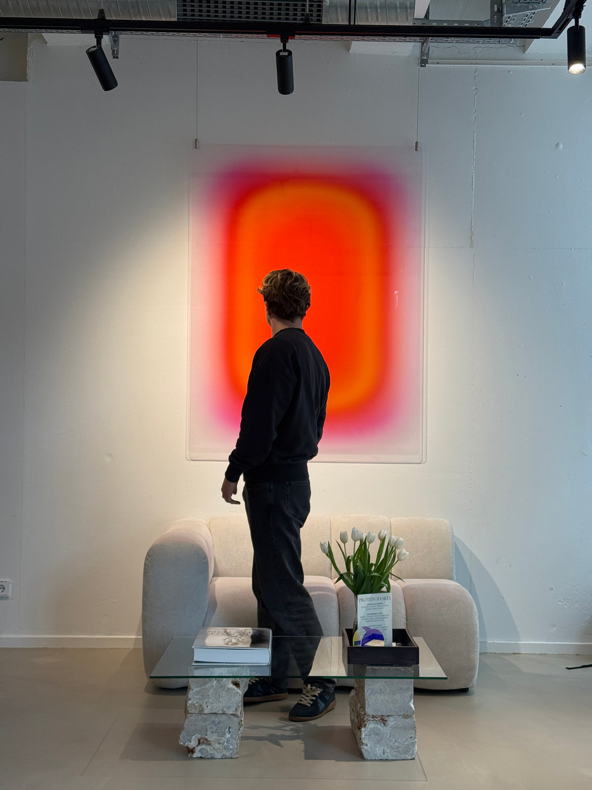 Luis West standing in front of a large orange acrylic glass artwork in the gallery
