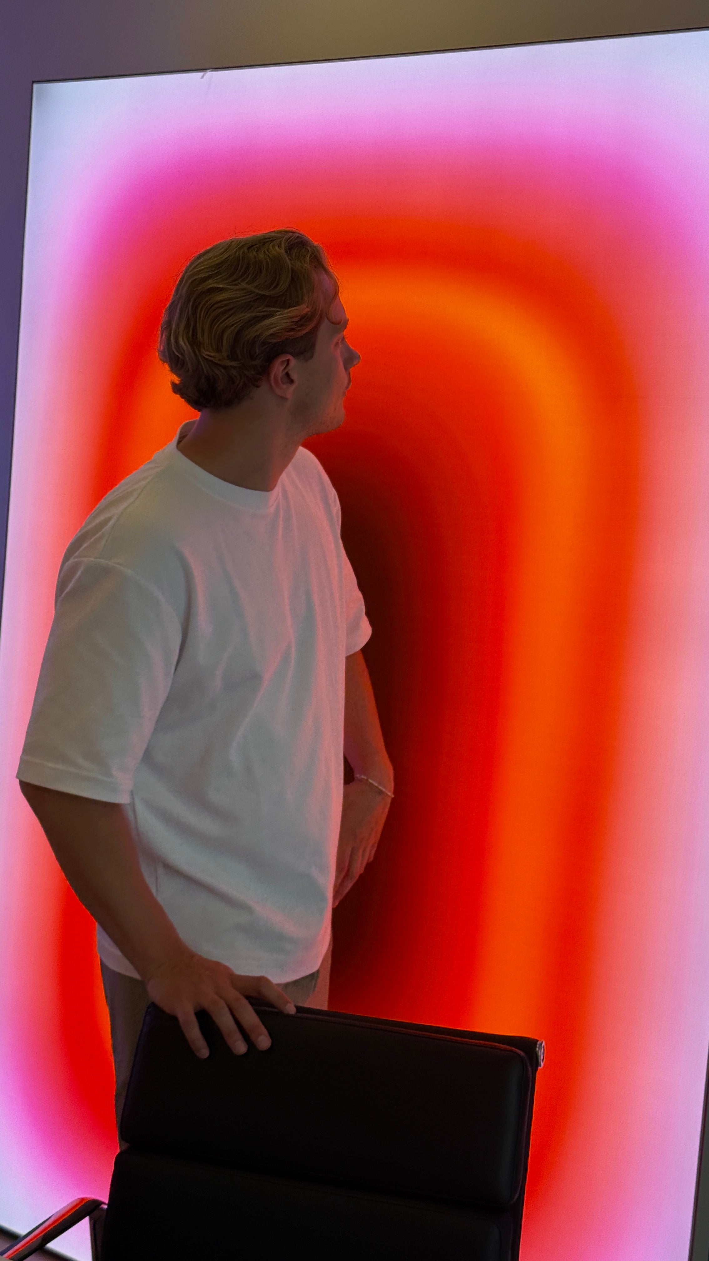 Luis West standing in front of the ORANGE PILL lightbox, canvas lit from within its frame