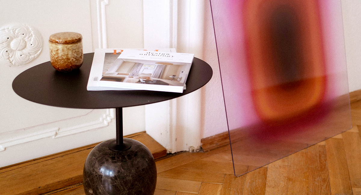 An acrylic glass artwork by Luis West leaning against the wall behind a side table