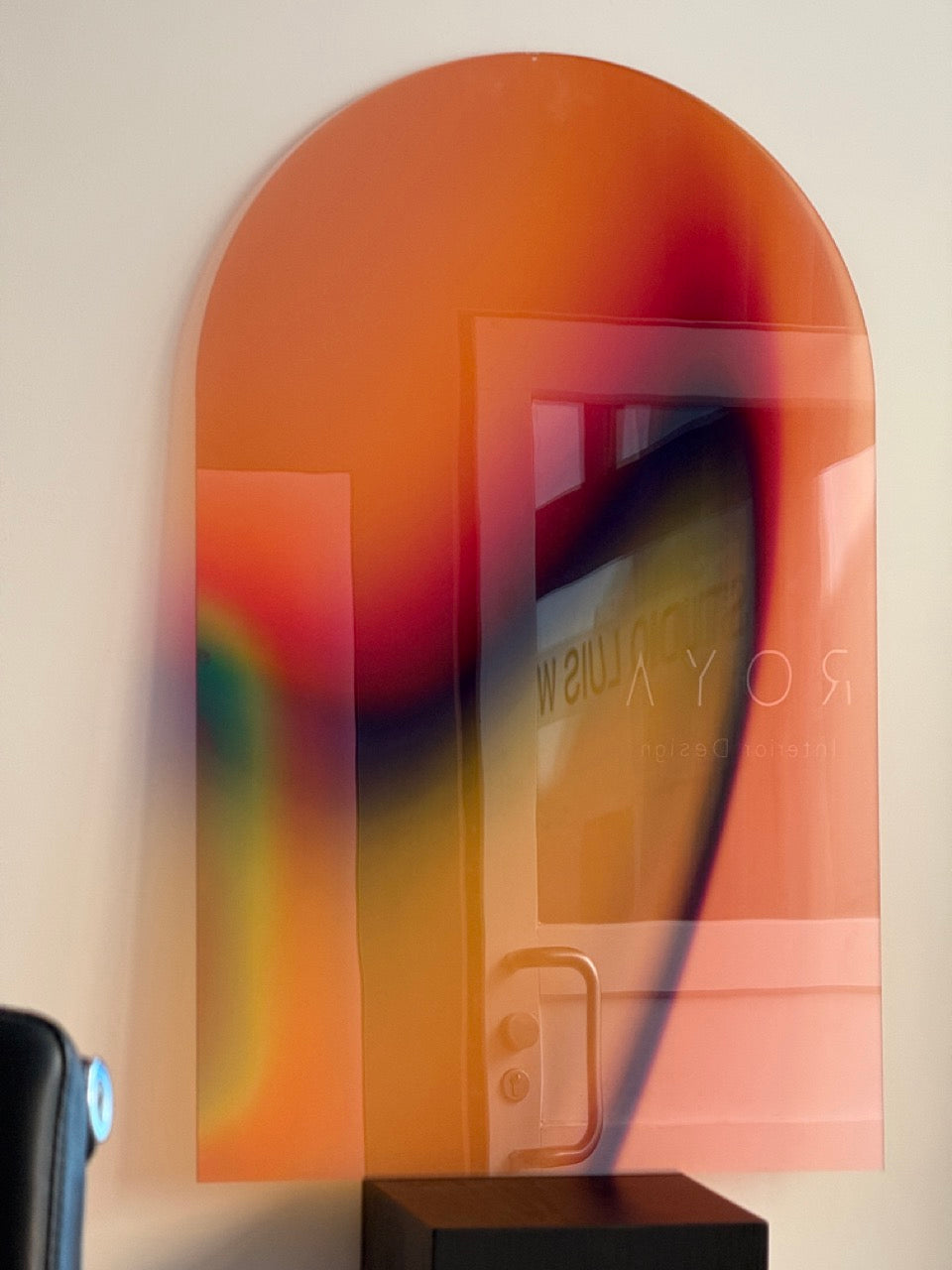 ARC by Luis West on the wall, the arched translucent acrylic glass reflecting a glass door opposite