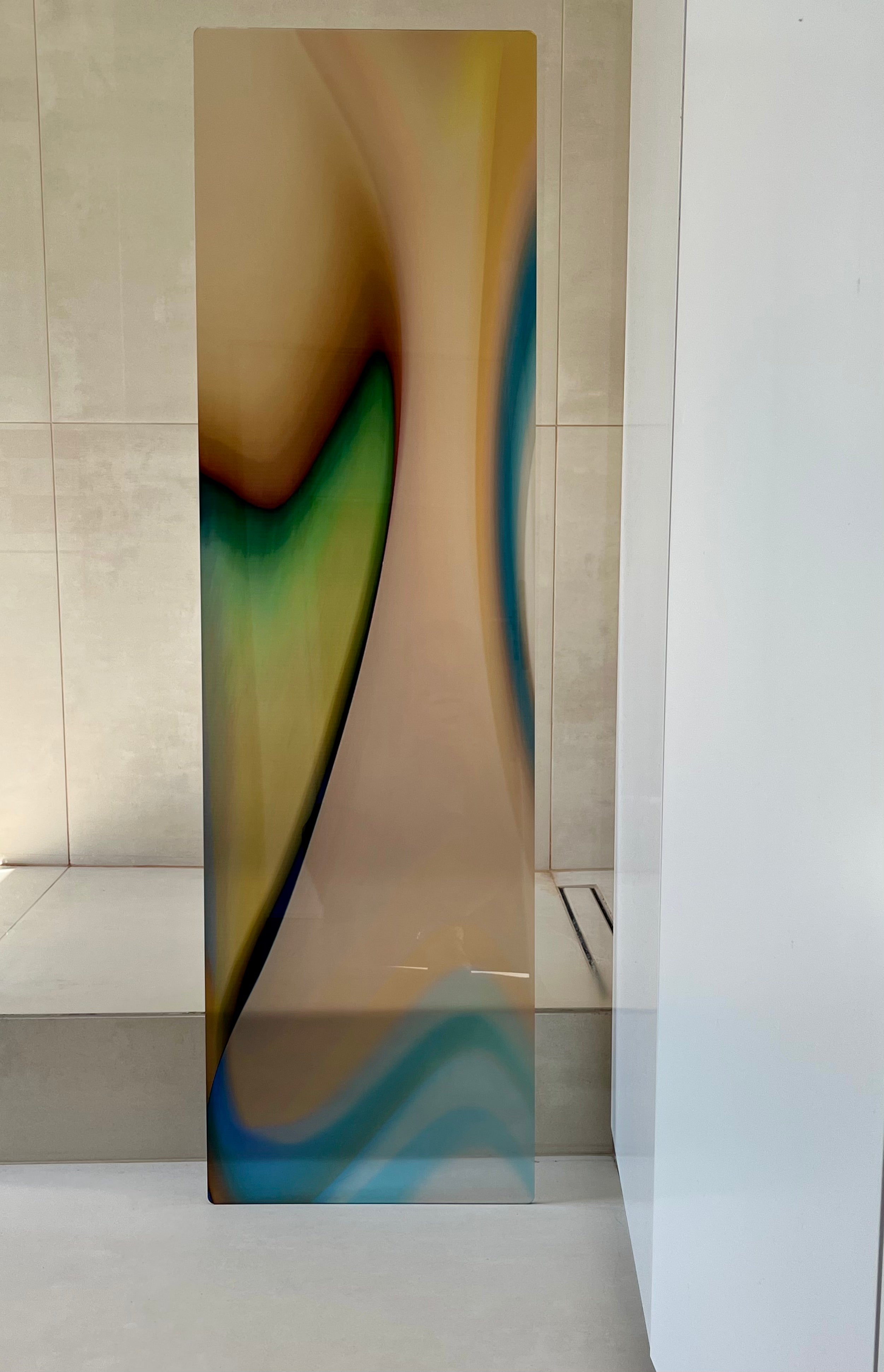 GREEN FLAME by Luis West, the tall translucent acrylic glass panel standing against a light tiled wall