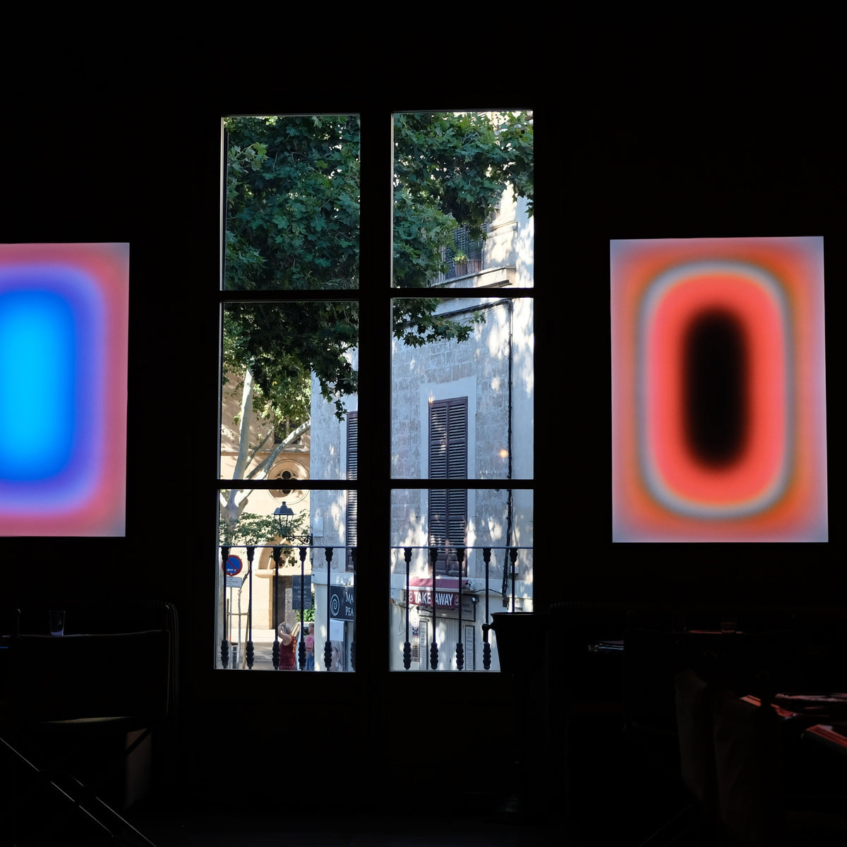 Two Luis West lightboxes flanking a window at the AETHOS exhibition on Mallorca